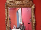 a mirror on the wall above a red radiator