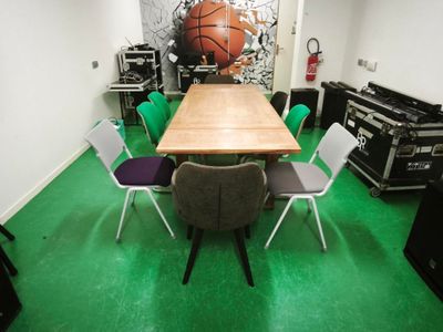 une table et des chaises dans une pièce où l'on peut voir une fresque représentant un ballon de basket sur le mur