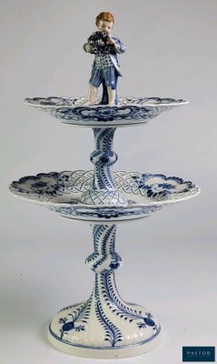 un présentoir à gâteaux bleu et blanc à trois étages, surmonté d'une figurine