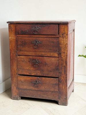 an image of a wooden chest of drawers with a plant in the corner