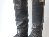 pair of black leather boots on white surface with white wall in background
