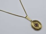 un gros plan sur un collier en or orné d'une pierre violette