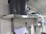 a trash can sitting on a metal shelf in a kitchen