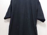 a black t - shirt hanging on a hanger against a white wall