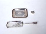 a silver tray with a spoon next to it on a white surface