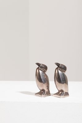 deux oiseaux en argent posés l'un à côté de l'autre sur une table blanche