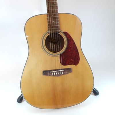 an acoustic guitar sitting on a stand against a white background