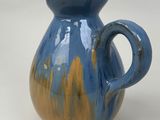 a blue and yellow vase sitting on a white surface