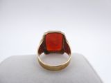 a close up of a gold ring with a red stone in it