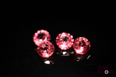 three pink crystal heart shaped beads on a black surface