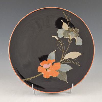 une assiette orange et noire ornée de fleurs et de feuilles