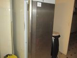 an image of a refrigerator in a kitchen with a trash can