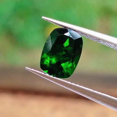 a close up of a green gemstone being held by a pair of pliers