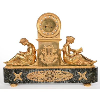 une horloge en or sur laquelle sont assises trois femmes