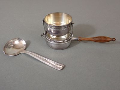une tasse en argent avec une cuillère et un repose-cuillère posés sur une table