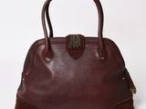 a brown leather handbag with a metal handle on a white background
