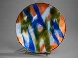a colorful plate on a metal stand on a gray surface
