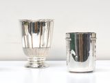 four silver vases are lined up on a white surface