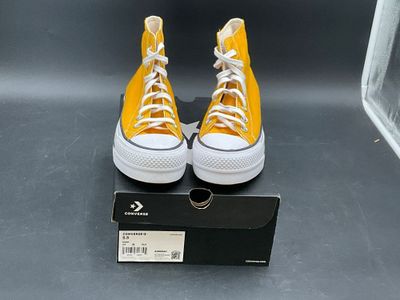 yellow converses with white laces are on display in front of a box