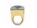 a close up of a gold ring with a blue topaz stone