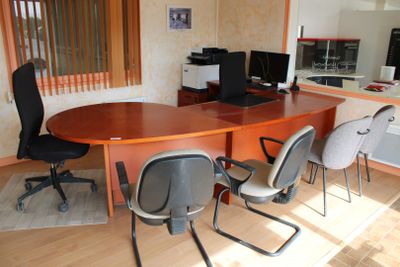 une table avec des chaises et un ordinateur posés dessus, dans une pièce