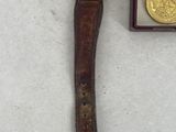 an image of a watch and medal laying on a white surface