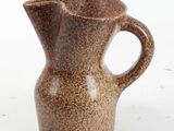 a small brown pitcher sitting on a white surface