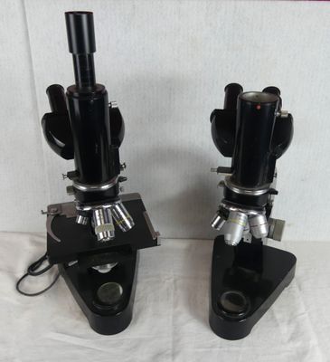 two microscopes are sitting side by side on a white surface