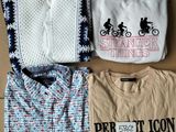 trois t-shirts et un pull sont posés sur une boîte en carton