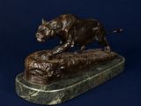 statue en bronze représentant un taureau posé sur un rocher, sur fond bleu