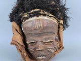 un gros plan d'un masque en bois aux cheveux noirs sur un fond blanc