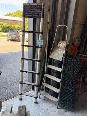 une échelle appuyée contre le mur, à côté d'un tas de bois