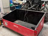 a large red box sitting in a garage with a tractor in the background