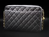 a black quilted bag with gold chains on a black background