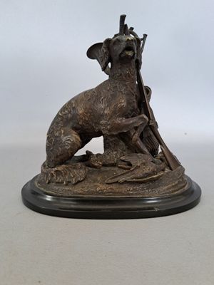 statue en bronze représentant un chien avec un pistolet posé sur une table