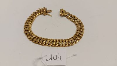 un bracelet en or muni d'une plaque, posé sur une table
