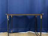 an image of a glass and brass console table with a blue curtain in the background