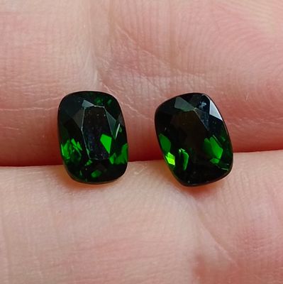 une paire de tourmalines vertes posées sur le doigt d'une personne