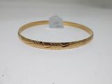 gros plan d'un bracelet en or sur une surface blanche