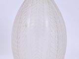 un vase en verre blanc orné d'un motif de feuilles