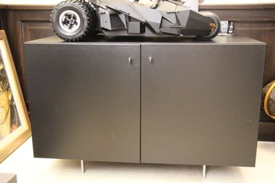 une Batmobile miniature posée sur une armoire dans une pièce