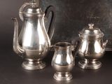three silver teapots and a coffee pot on a table