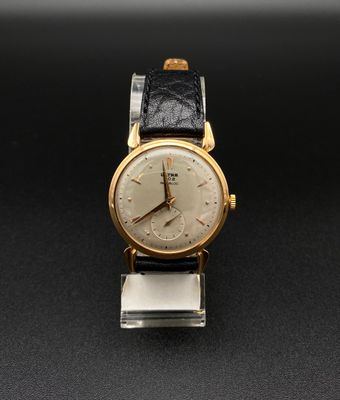 une vieille montre-bracelet en or avec un bracelet en cuir noir