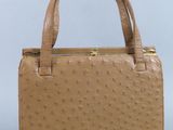 un sac à main en cuir d'autruche beige avec des finitions dorées