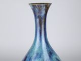 blue and green glass vase on a white surface with a gray background