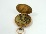 a small gold pocket watch with a key in it