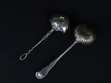 pair of silver spoons on a black surface with a black background