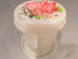 un petit vase blanc orné de fleurs roses