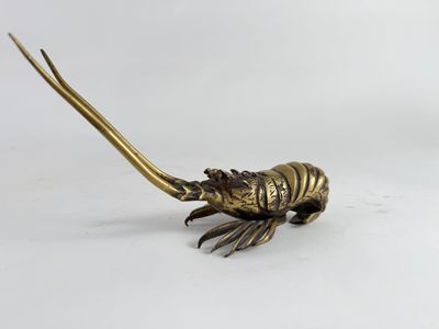 un gros plan d'une statue en laiton représentant un homard sur fond blanc