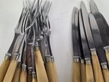 several forks and knives are lined up on a white surface